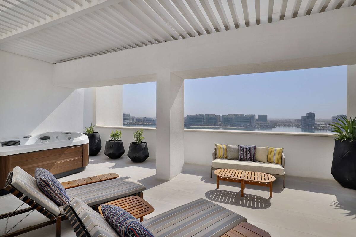 Eine Dachterrasse mit Whirlpool, Liegestühlen, einer Sitzecke und Topfpflanzen.
