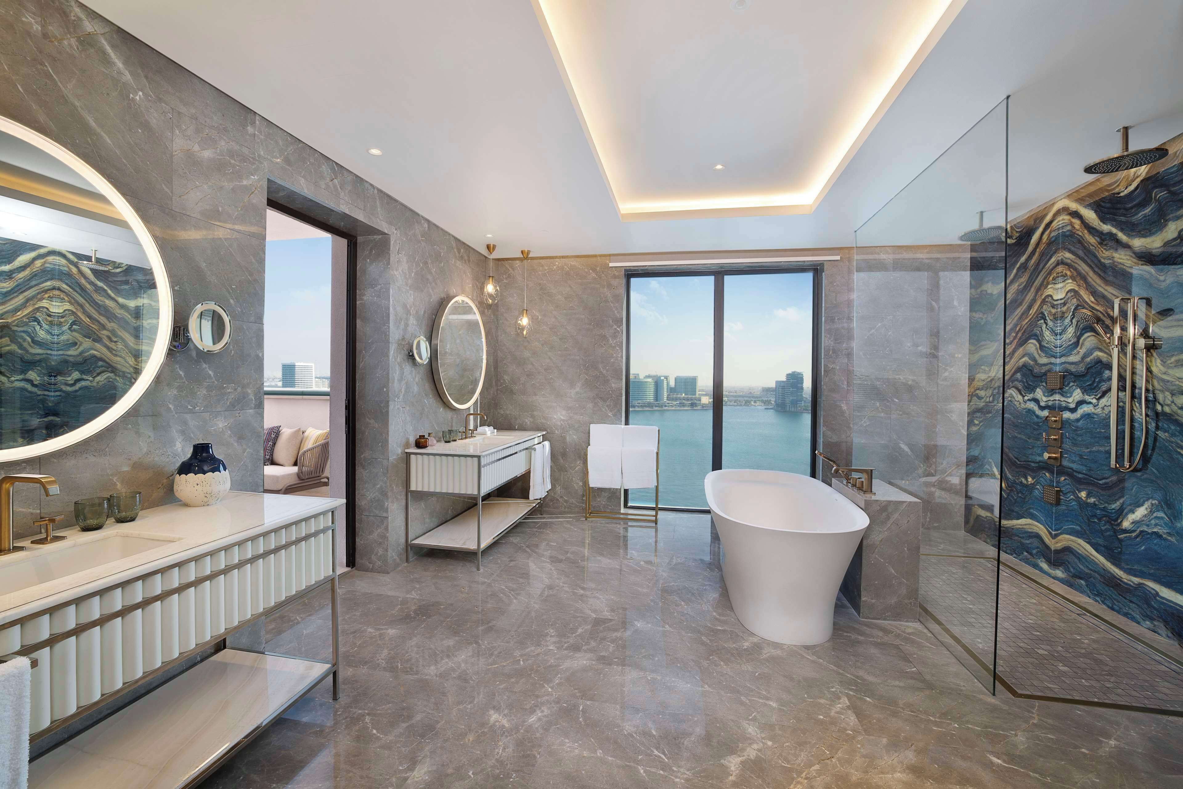A modern bathroom with a large bathtub, a glass-enclosed shower, and a vanity with a mirror.