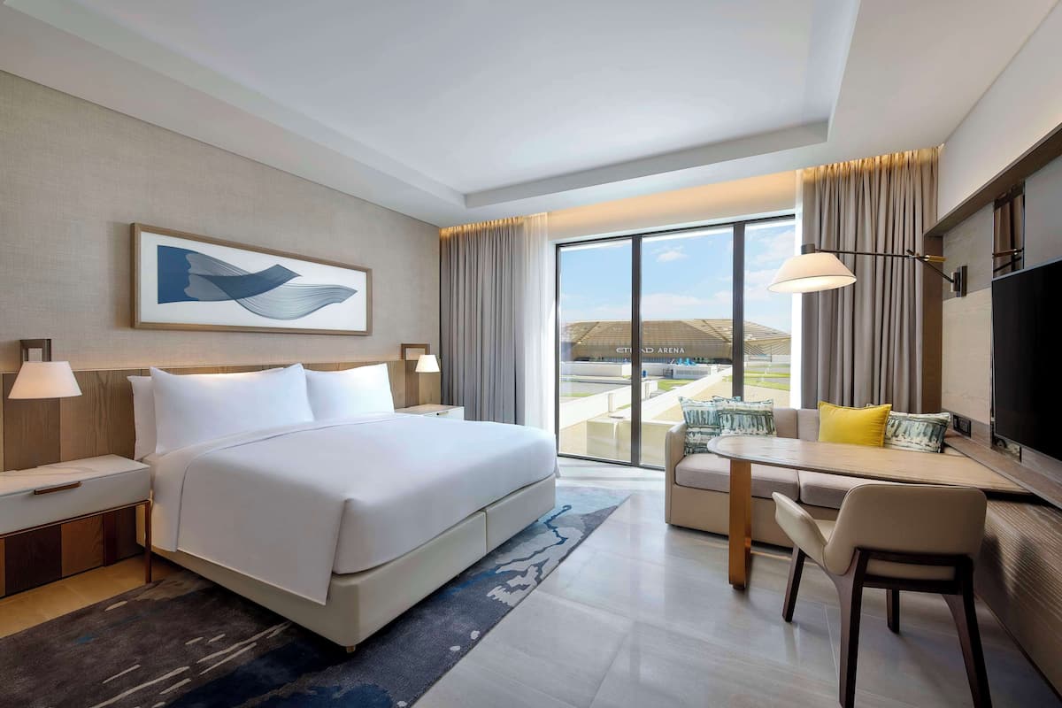 Ein modernes Hotelzimmer mit einem großen Bett, einem Schreibtisch und Blick auf die Stadt.