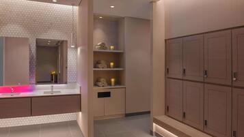 A modern bathroom with a hexagonal tile backsplash, a vanity with a pink-lit sink, and a built-in shelving unit with towels and candles.