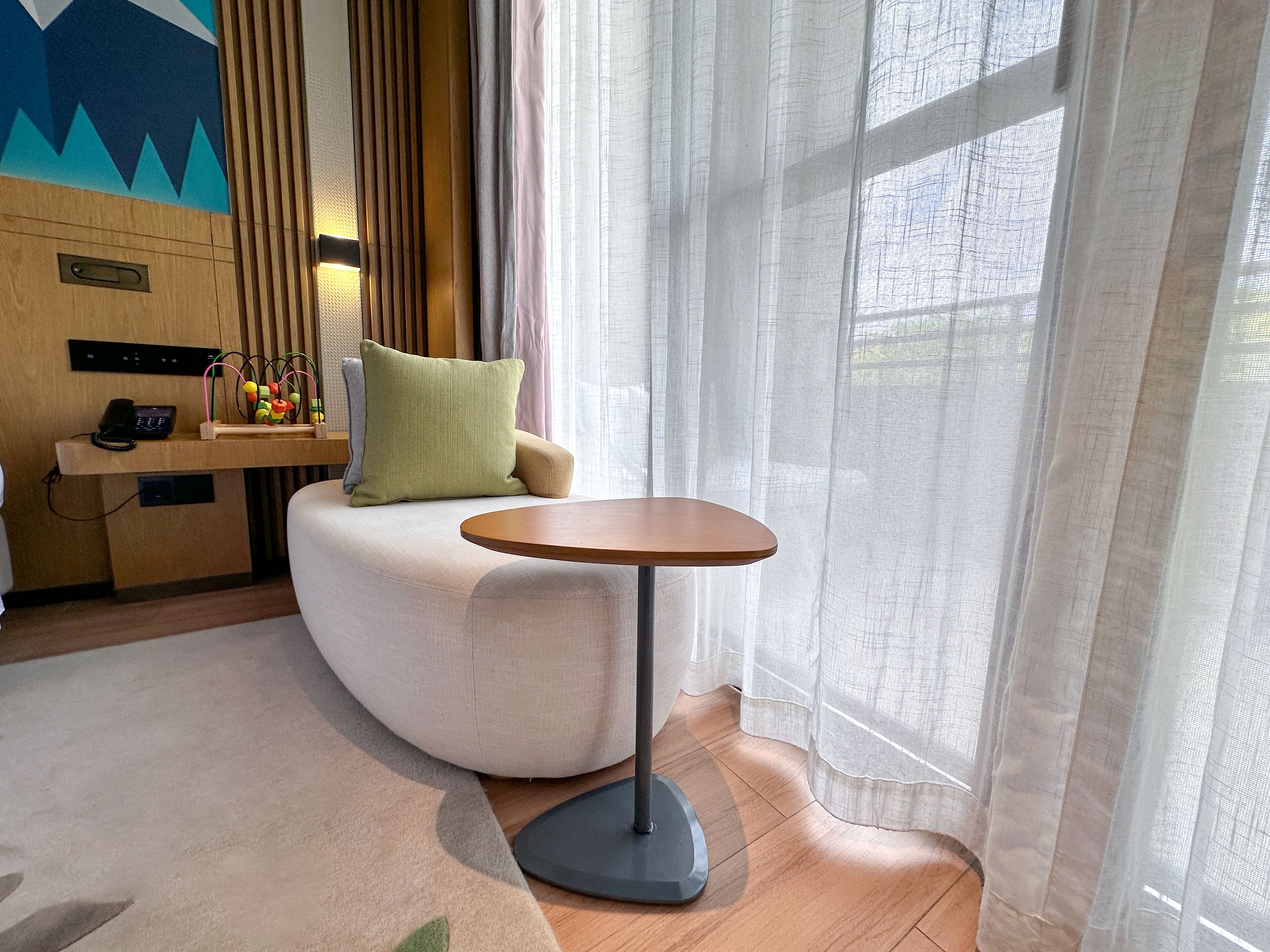 Una habitación moderna con un sofá curvo, una pequeña mesa redonda y suelo de madera.