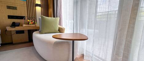 Una habitación moderna con un sofá curvo, una pequeña mesa redonda y suelo de madera.