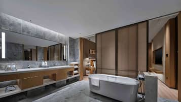A modern bathroom with a large mirror, two sinks, a bathtub, and wooden cabinetry.
