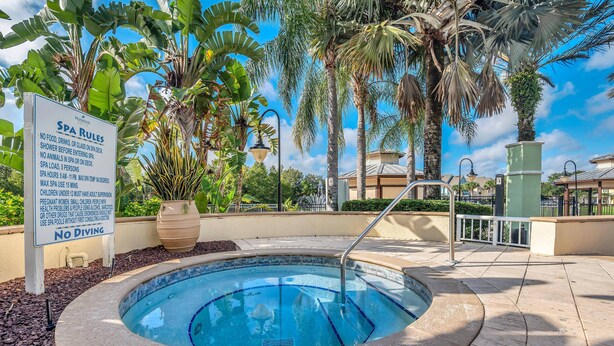 A hot tub surrounded by palm trees and a sign with spa rules. - 2 Bedroom Vacation Condo (2011) (Kissimmee)