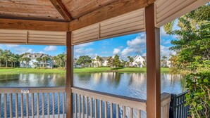 A covered deck with a view of a lake and houses in the background. - 2 Bedroom Vacation Condo (2011) (Kissimmee)
