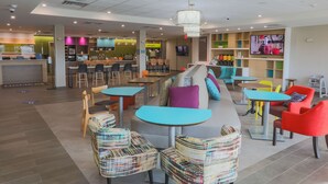 Ein stilvoller Lounge-Bereich mit Sitzgelegenheiten, einer Theke und einem Fernsehbildschirm.