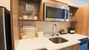 A modern kitchen with a stainless steel refrigerator, a built-in microwave, a sink, and a coffee maker.