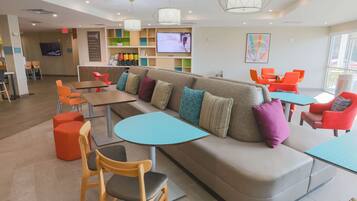 Ein stilvoller Lounge-Bereich mit einer Couch, Sesseln, Tischen, einem Fernseher und einer Bar.