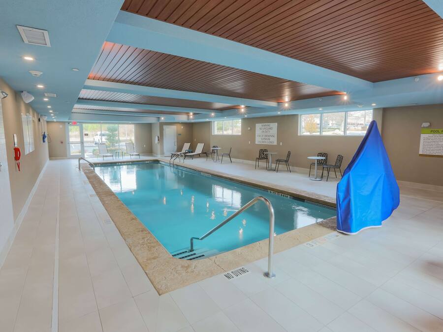 Una piscina interior con normas claramente expuestas, sillas de descanso y una zona cubierta.