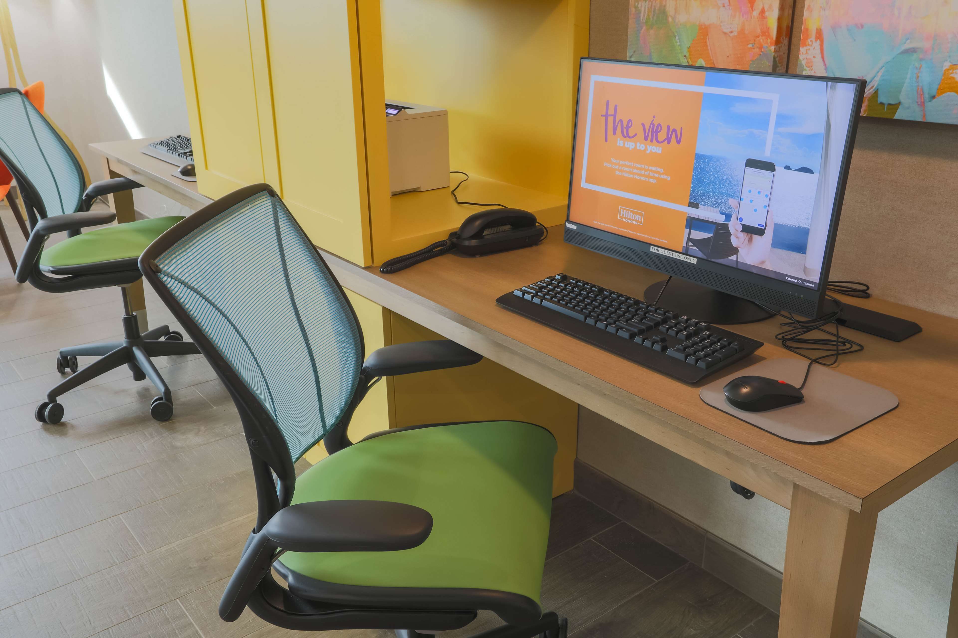 Un espacio de trabajo con una computadora, teclado, ratón y dos sillas de oficina.