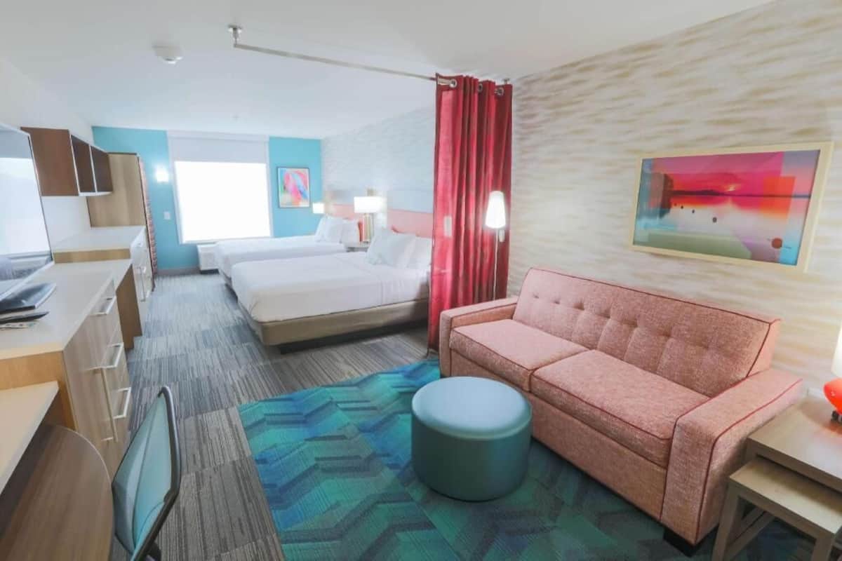 Una habitación de hotel con cama, sofá, escritorio y una silla.