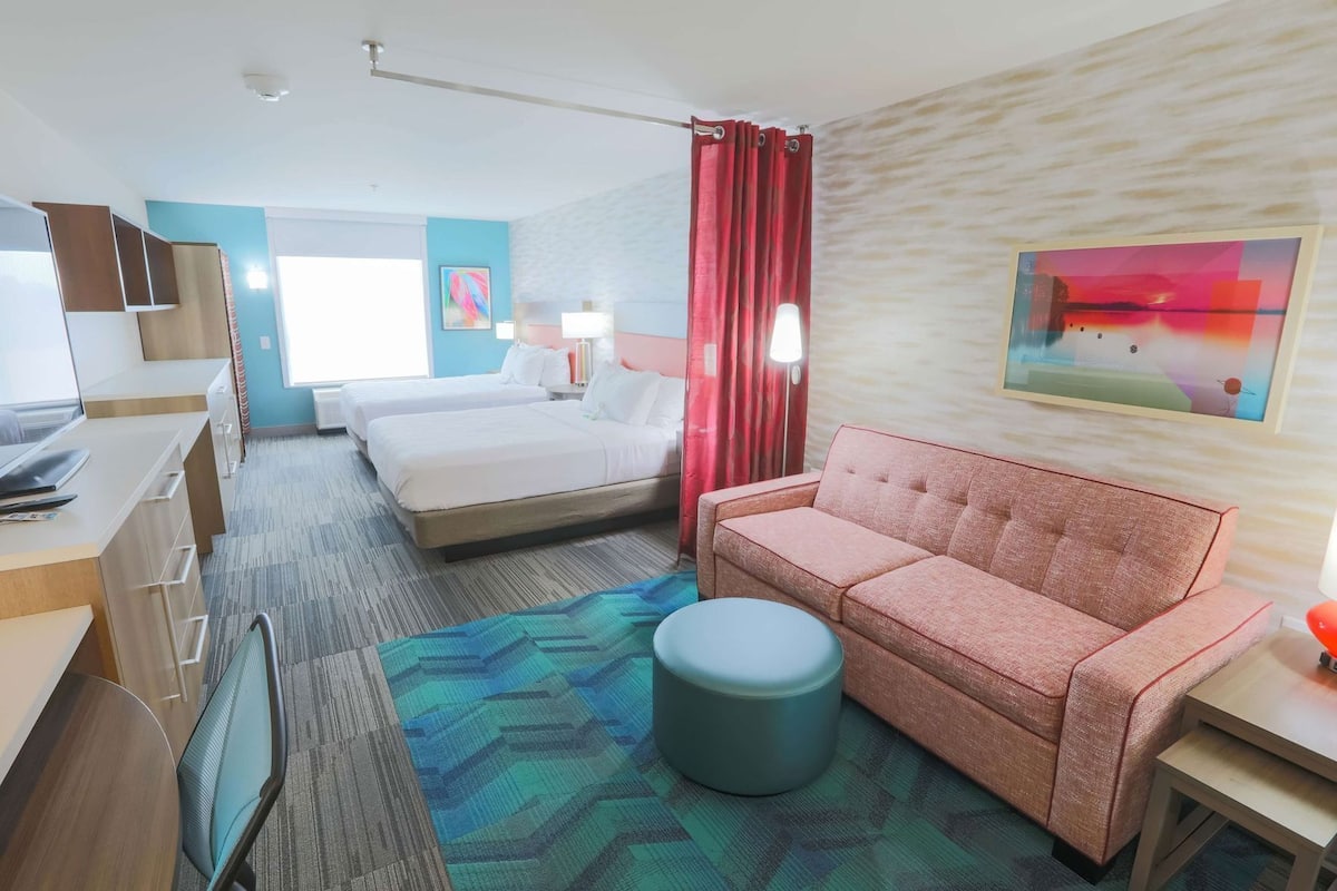 Una habitación de hotel con cama, sofá, escritorio y una silla.