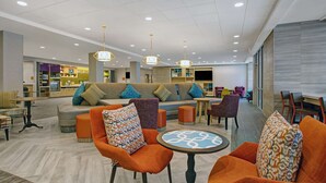Un vestíbul d'hotel modern amb zona de seients, televisió i taulell de recepció.