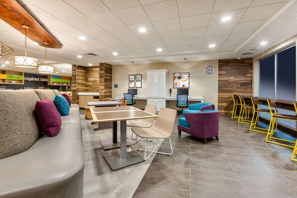 A modern lounge area with a sofa, chairs, a table, and a TV screen.