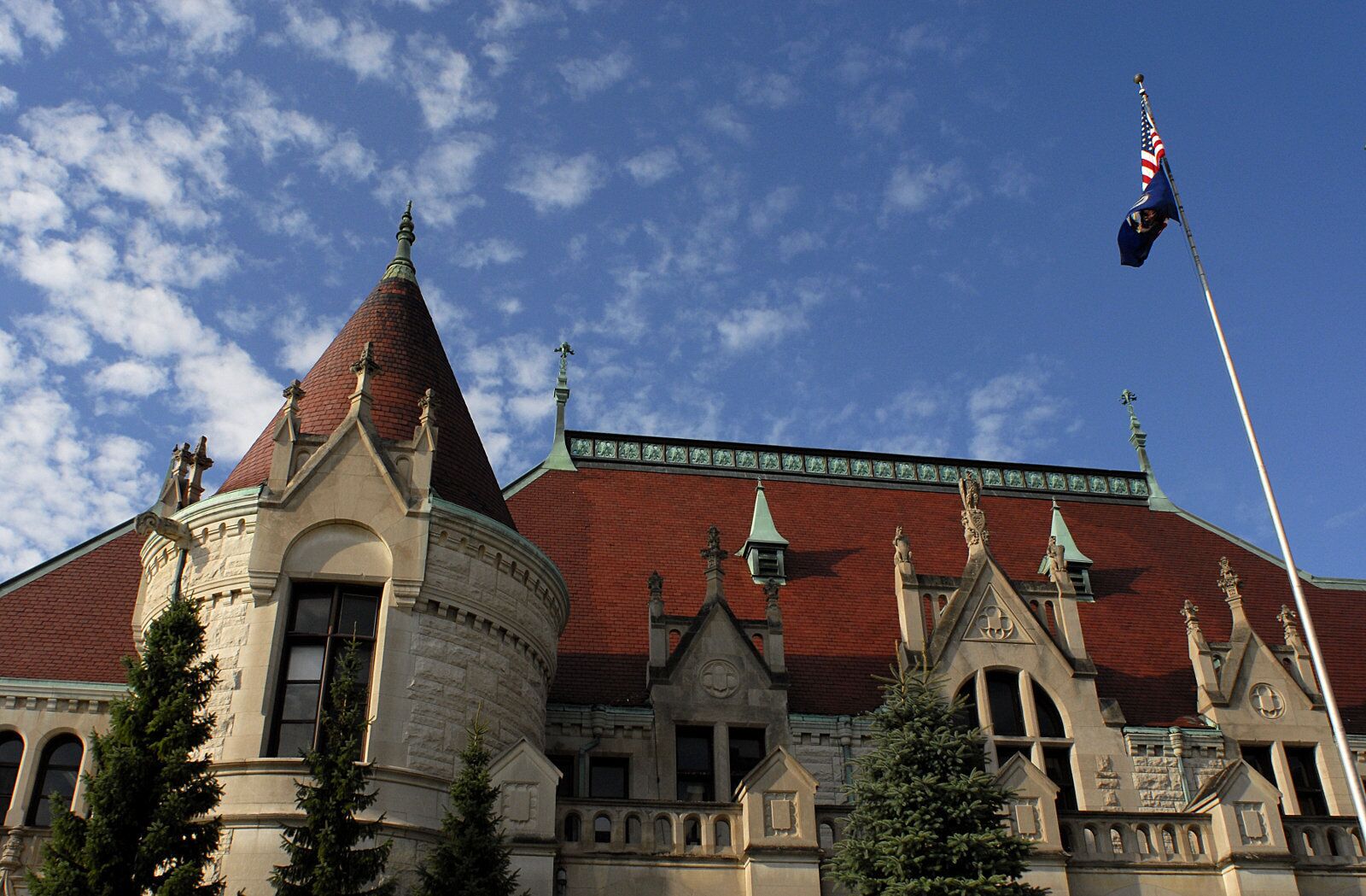 A historic building with a prominent tower, a flagpole with an American flag, and a clear blue sky.