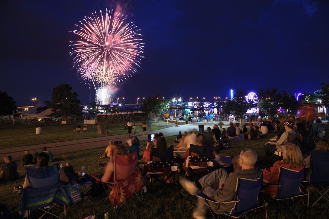 An outdoor event with a crowd watching fireworks.