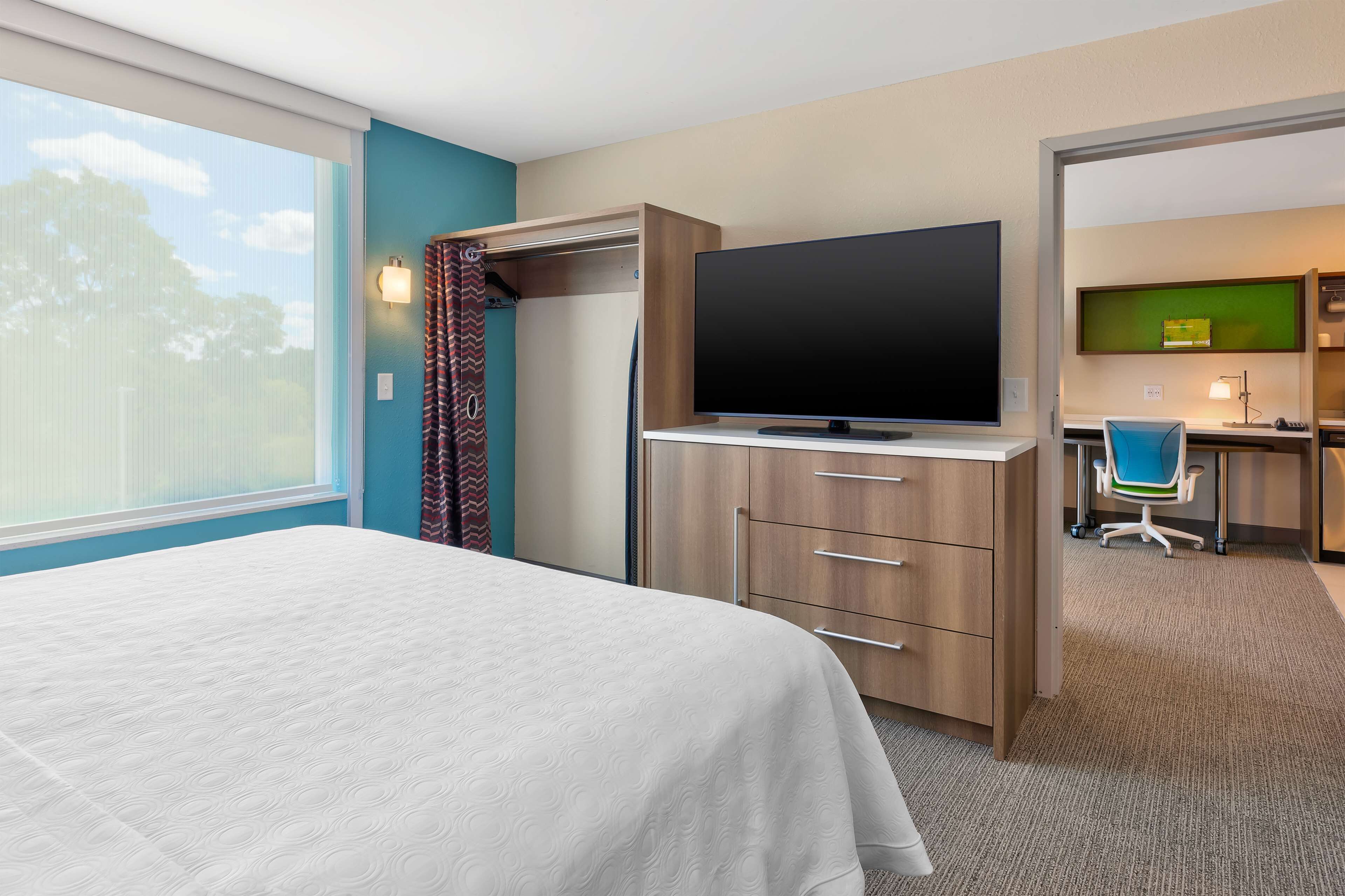 Ein Hotelzimmer mit Bett, Fernseher, Schreibtisch und Stuhl sowie Blick ins Freie.