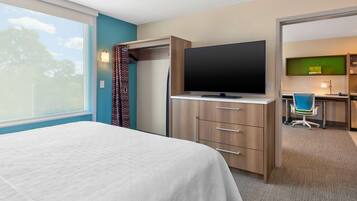 Ein Hotelzimmer mit Bett, Fernseher, Schreibtisch und Stuhl sowie Blick ins Freie.
