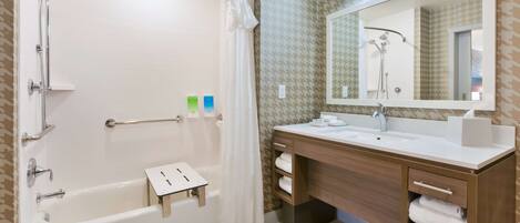 A modern bathroom with a bathtub, shower, vanity, and a large mirror.