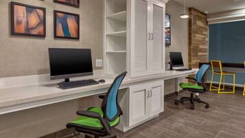A reception area with a desk, computer, chairs, and a storage unit.