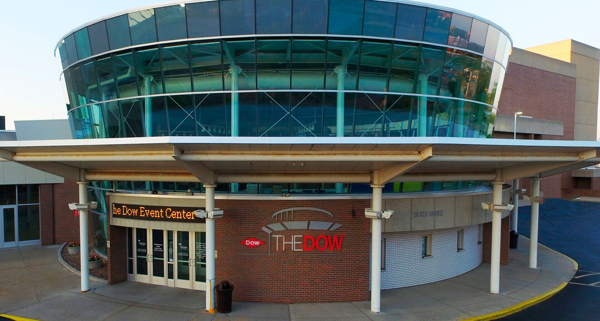 A modern building with a glass facade and a covered entrance labeled "The Dow Event Center."