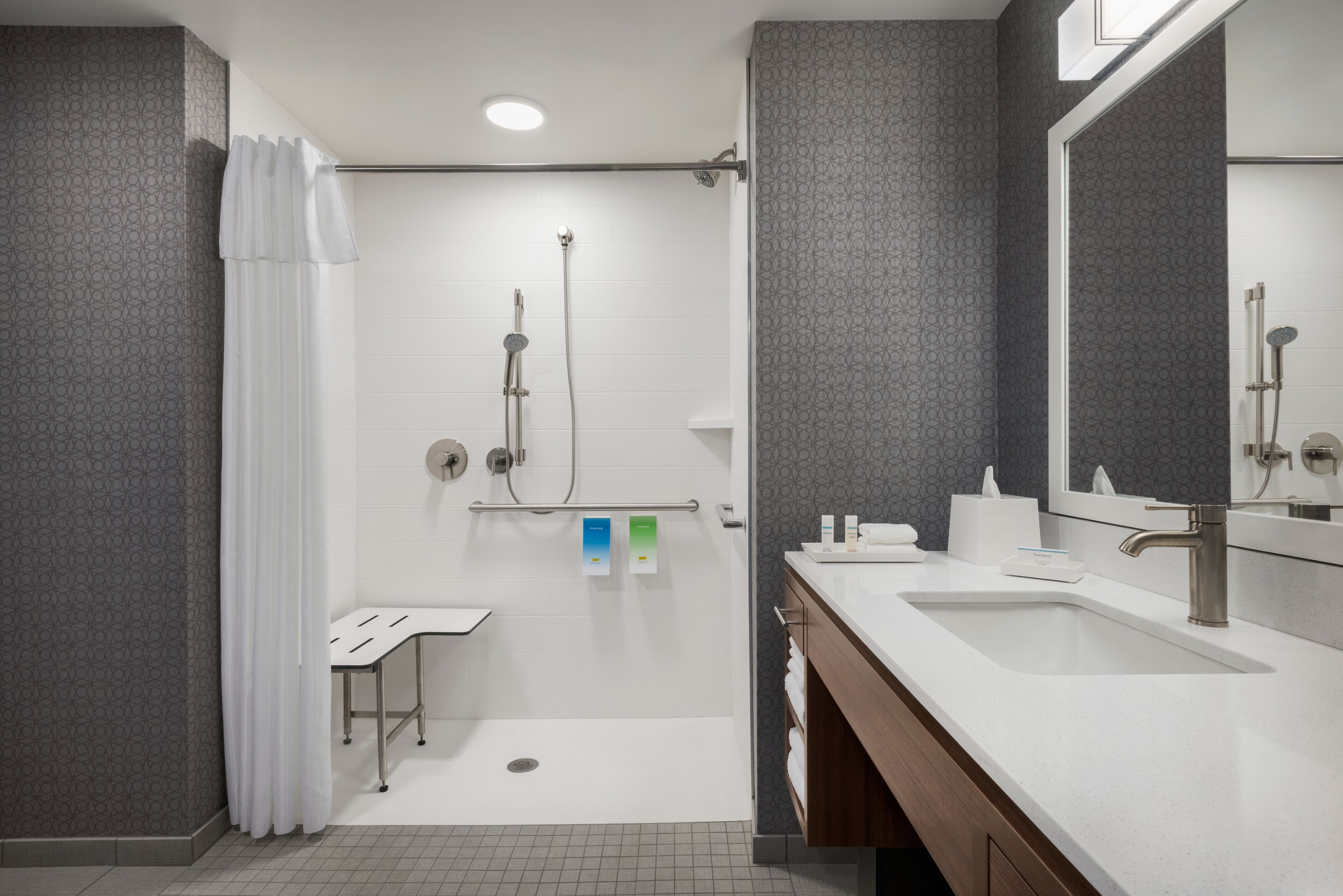 A modern bathroom with a shower, a sink, and a mirror.