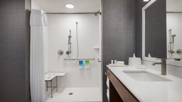A modern bathroom with a shower, a sink, and a mirror.
