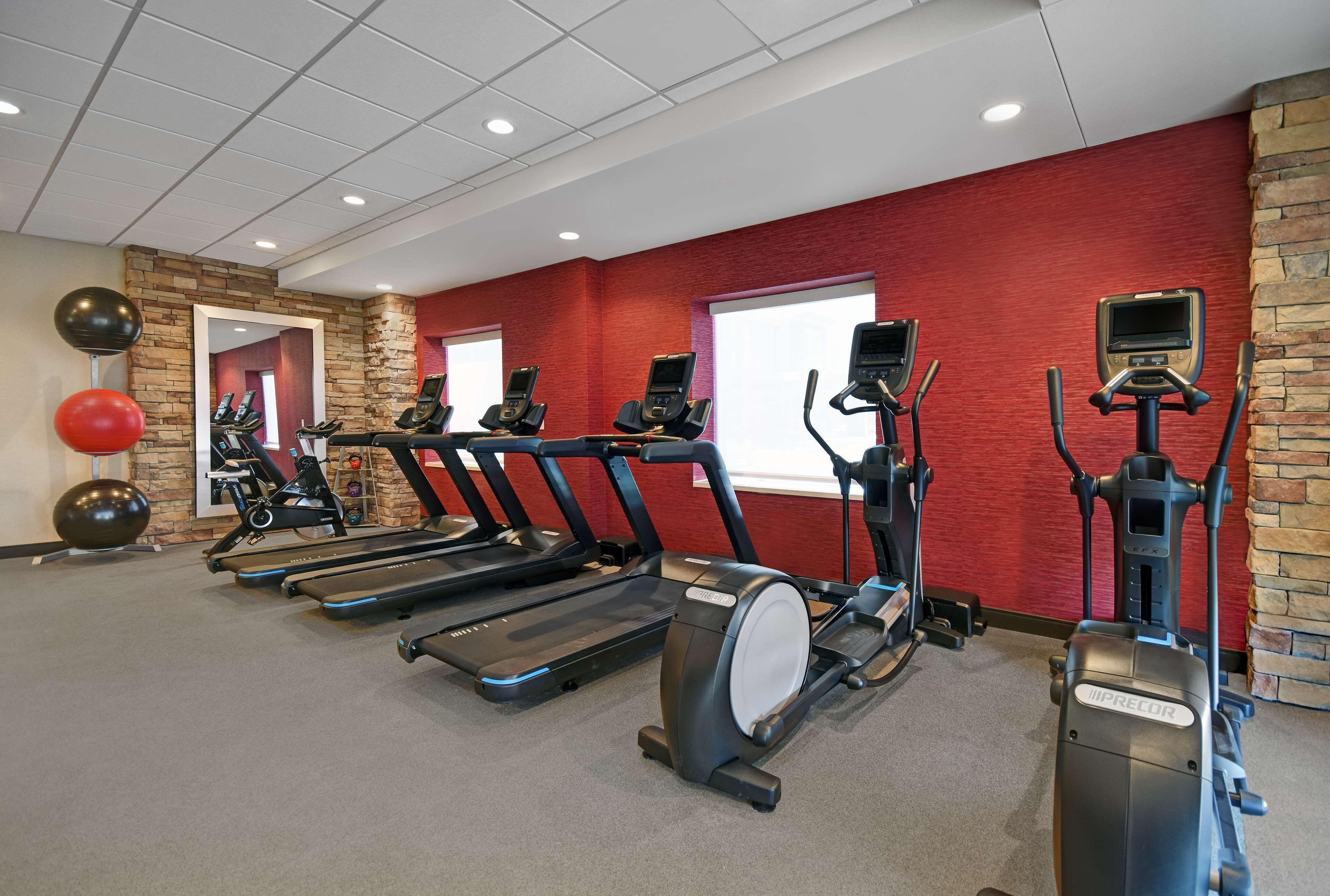 A gym with treadmills, elliptical machines, and exercise balls.