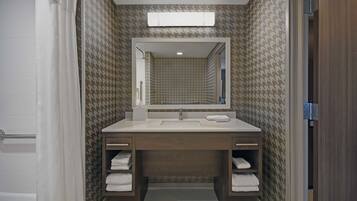 A bathroom with a double sink vanity, a mirror above the sink, and towel racks.