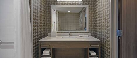 A bathroom with a double sink vanity, a mirror above the sink, and towel racks.