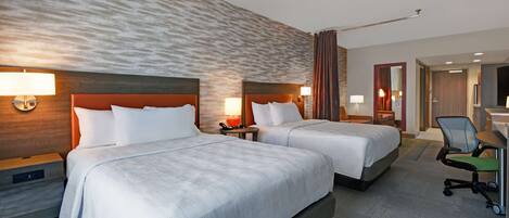 A hotel room with two beds, a desk, and a chair.