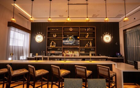 A bar area with a counter, bar stools, and a television screen displaying 'B55'.