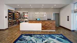 A hotel reception area with a wooden reception desk, a welcome sign, and a shoe display. - Hampton Inn & Suites by Hilton Waterloo St. Jacobs (Township of Woolwich)