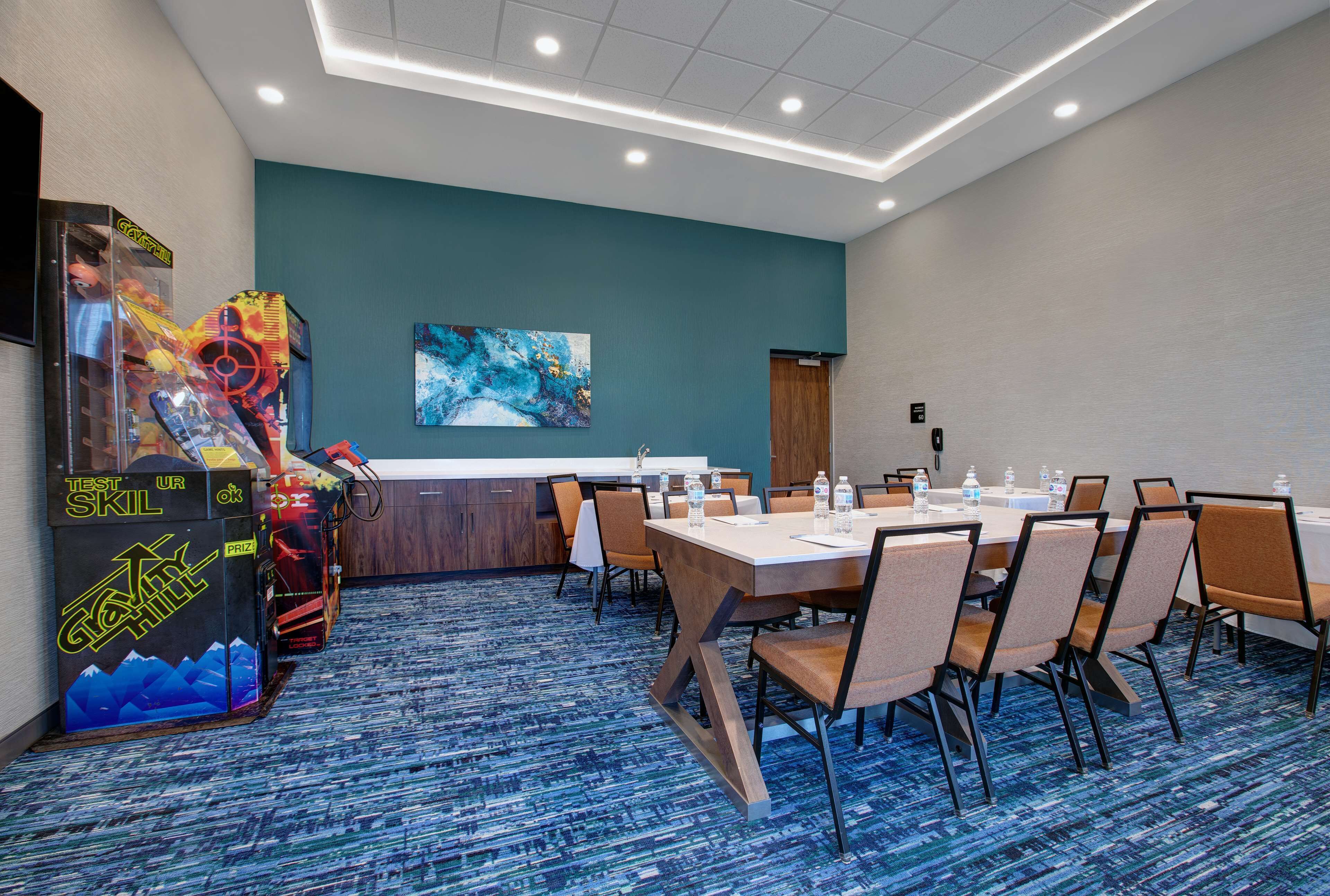 A conference room with a long table, chairs, and a carpeted floor.