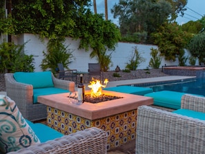 Un patio con una chimenea, mobiliario exterior y una piscina.