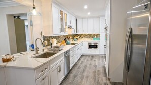 Une cuisine moderne avec des meubles blancs, des appareils en acier inoxydable et un plancher en bois.