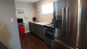 A modern kitchen with stainless steel appliances, a microwave, and a red trash bin.