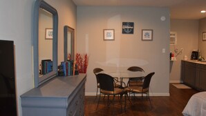 A dining area with a round table and chairs, a dresser, and a mirror.