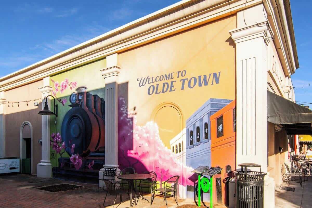 A mural with 'Welcome to Olde Town' text and a vintage train on a building facade.