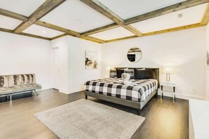Ein Schlafzimmer mit einem Bett, einer Schlafcouch, einem runden Spiegel und einem Nachttisch.