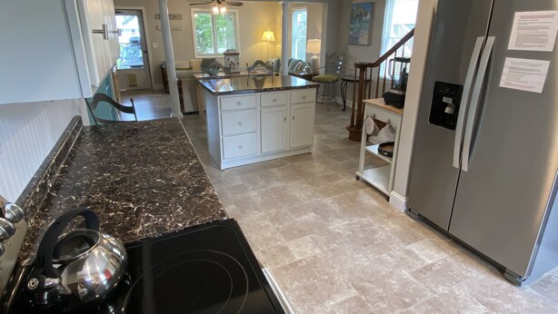 A modern kitchen with a central island, stainless steel appliances, and a chandelier.
