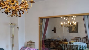 A living room with a chandelier, a sofa, a coffee table, and a dining area with a table and chairs.