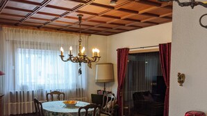 A dining area with a wooden table, chairs, a chandelier, and a red rug.