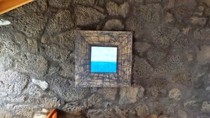 A stone wall with a framed picture of the sea.