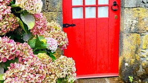 A red door with a 'Clean & Safe' sign, a stone wall, and a tiled roof.