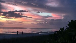 A beach scene with people walking along the shore and a sunset in the background. - PARADISE FOUND! NOW BOOKING FOR 2026! (Naples)