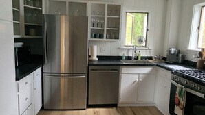 A modern kitchen with white cabinetry, stainless steel appliances, and a window providing natural light. - CENTRAL A/C!!! Huge Downtown Historic CVX Home! Walk to town & beach! (Charlevoix)