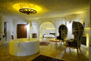 A luxurious room with a large bathtub, a wooden door, and a decorative chair. - Nar Cave House (Nevşehir)