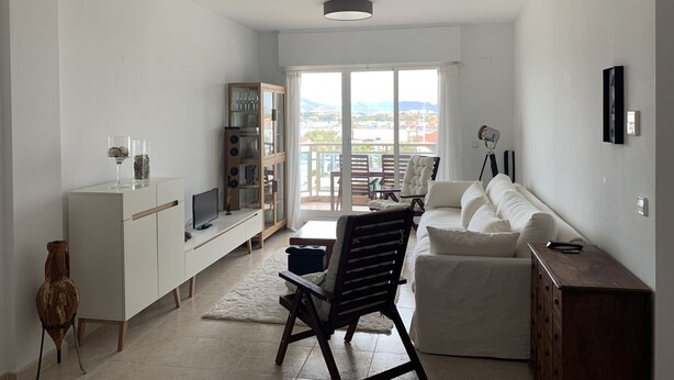 A modern living room with a white sofa, a wooden cabinet, a TV, and a dining area with a table and chairs. - Nice and cozy apartment, private parking and sea views in Cabo de Palos. (Cabo de Palos)