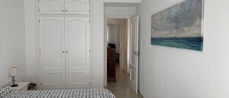 A bedroom with a bed, a painting, and a wardrobe.